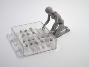 gray human figurine choosing from assortment of plastic injection molded hands