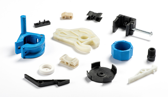 Many different injection plastic parts of white, blue and black color spread on white background