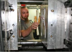 an operator at Rex Plastics removes a part for a multi cavity mold that uses 2 cavities. 