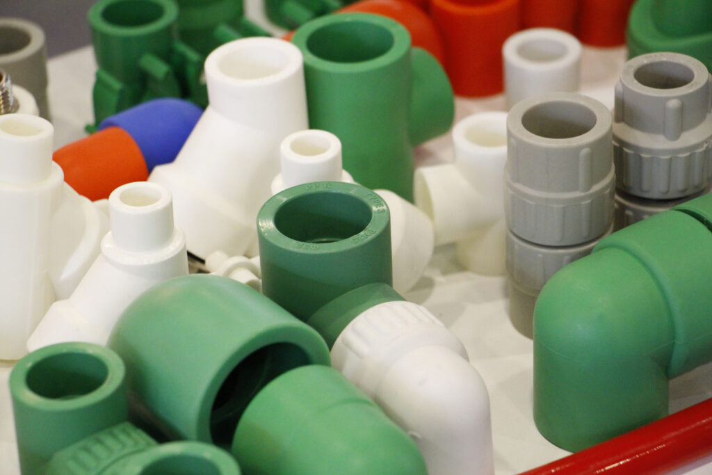 Many colored plugs, screws, valves, fittings, pipes, plastic adapters.