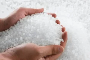 Someone is scooping up a handful of opaque polyethylene plastic pieces. It's a closeup of their hands.