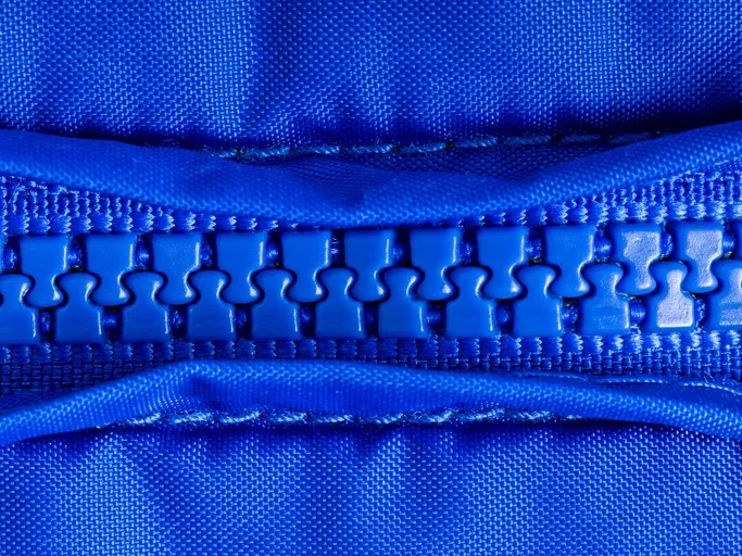 A close up of a blue zipper that's closed. The zipper is made of polyamide, also known as nylon.
