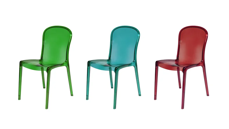 Three transparent, acrylic chairs are lined up on a white background. They are each a different color: green, blue, and red.