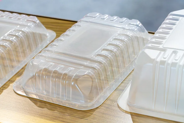 An upturned, opaque plastic food tray on a wooden table.