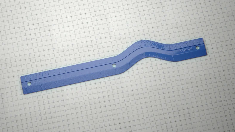 A blue ruler with a warped defect, making it curved at one end instead of completely straight.